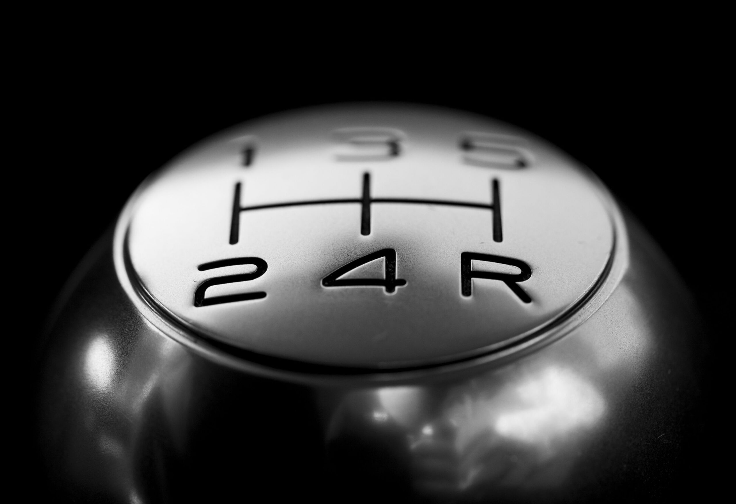 Close-up of a manual transmission shift knob with H-pattern gear diagram