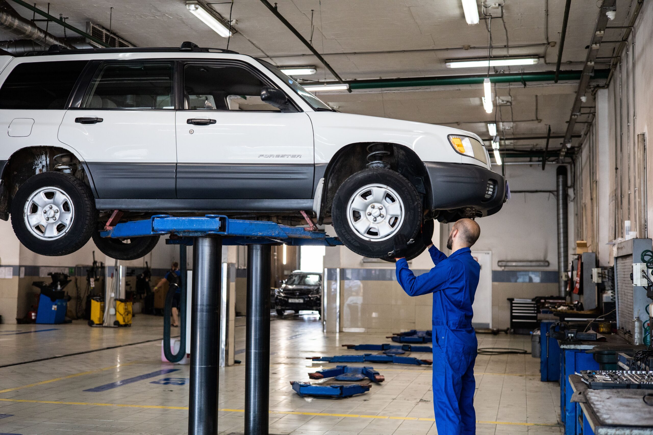 Mechanic inspecting a car on a lift in a repair shop