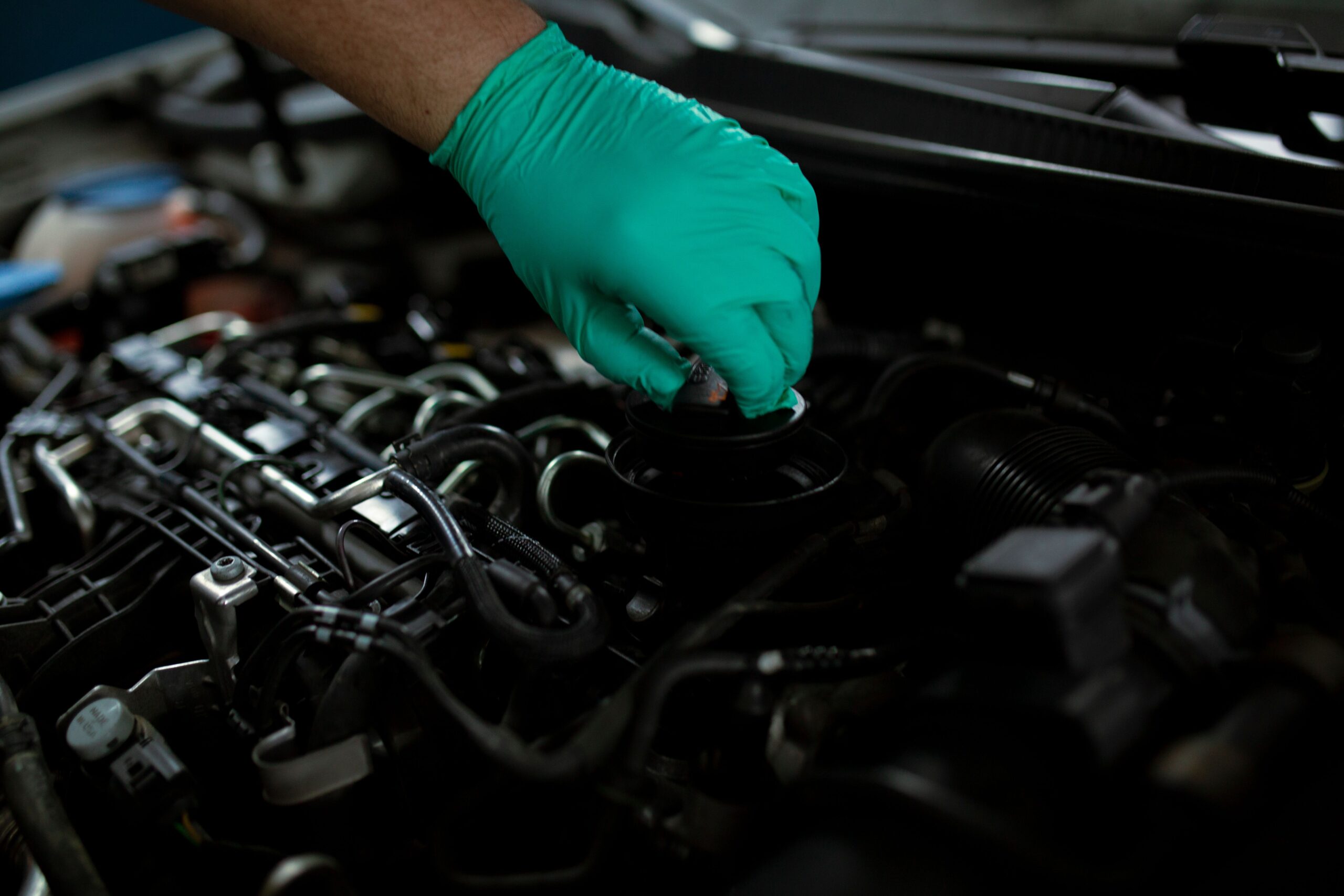 Gloved hand opening an engine oil filler cap